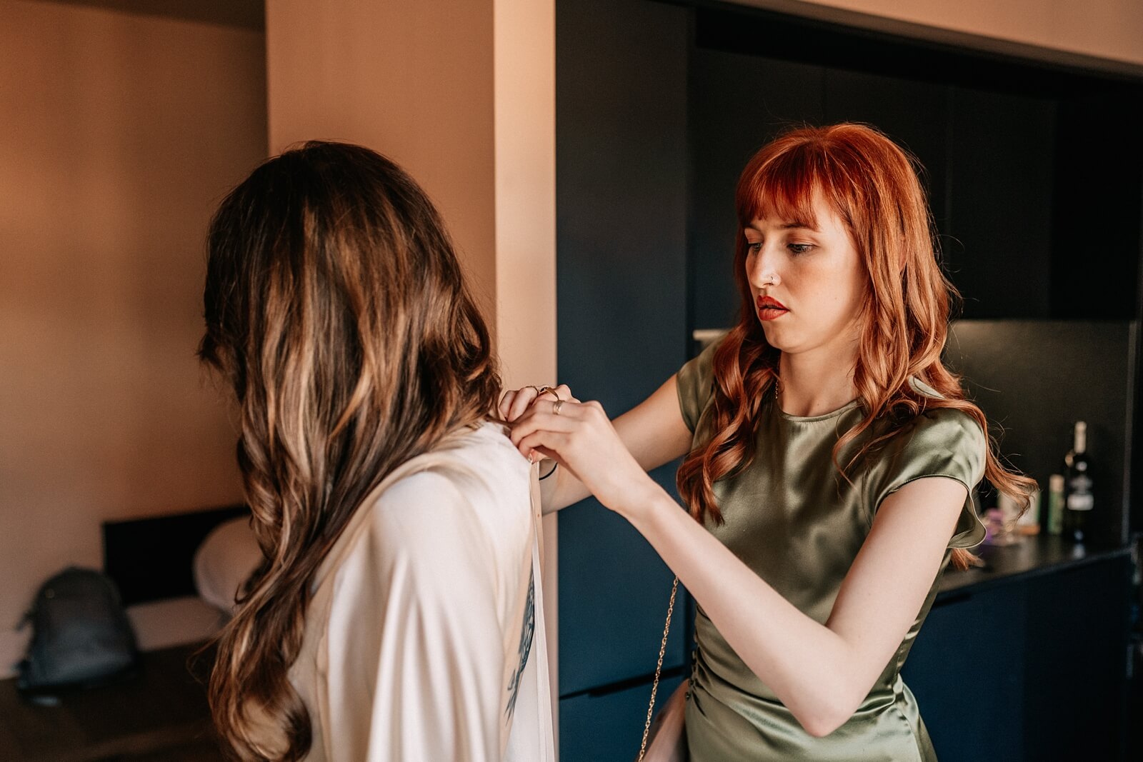 Bridesmaid helping bride into vintage dress